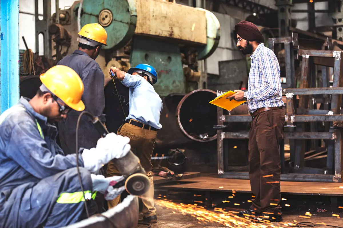 Workers operating heavy machinery in a small manufacturing unit highlighting MSME sector growth under India–EU free trade agreement