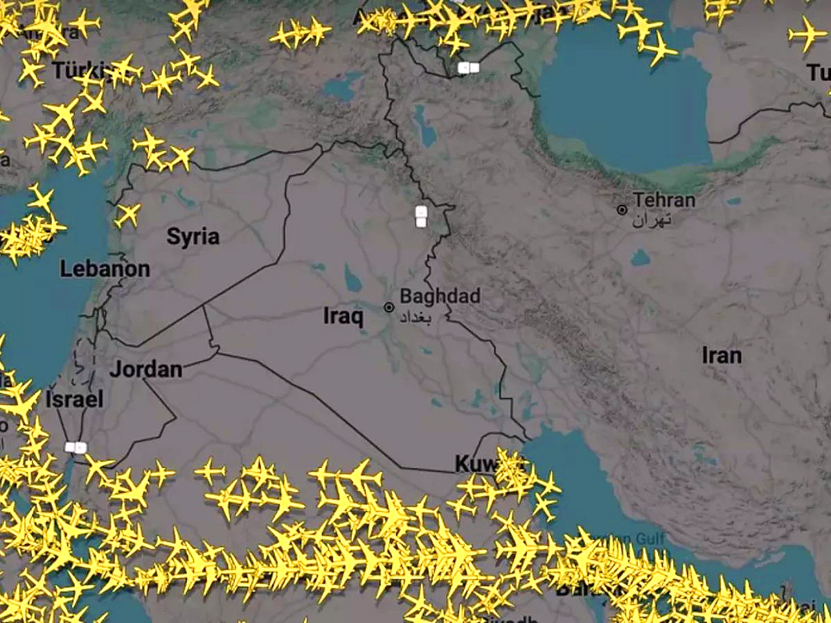 Close-up Flightradar24 map focused on Iraq, Iran, Kuwait, and surrounding areas. Yellow airplane icons form a dense ring around the Persian Gulf and borders, completely avoiding the interior over Iran (Tehran marked), Baghdad (Iraq), and Kuwait, creating a clear empty corridor in the closed airspace amid ongoing conflict.