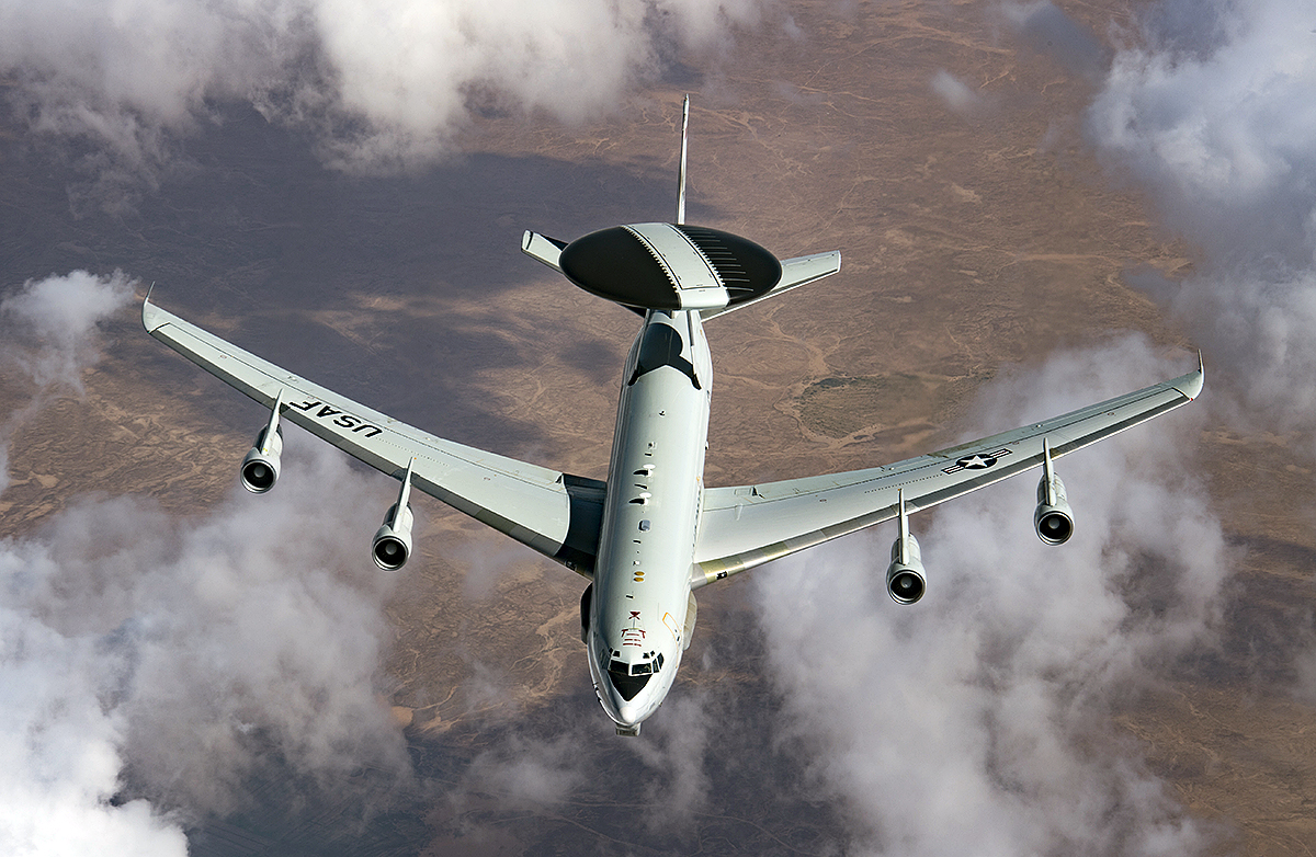 US Air Force E-3 Sentry AWACS aircraft flying with radar dome over desert