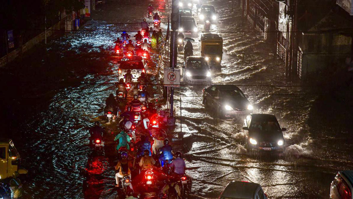 హైదరాబాద్ నగరంలో భారీ వర్షం తర్వాత నీటితో నిండిన రోడ్డుపై ట్రాఫిక్‌లో సాగుతున్న వాహనాలు రాత్రి దృశ్యం