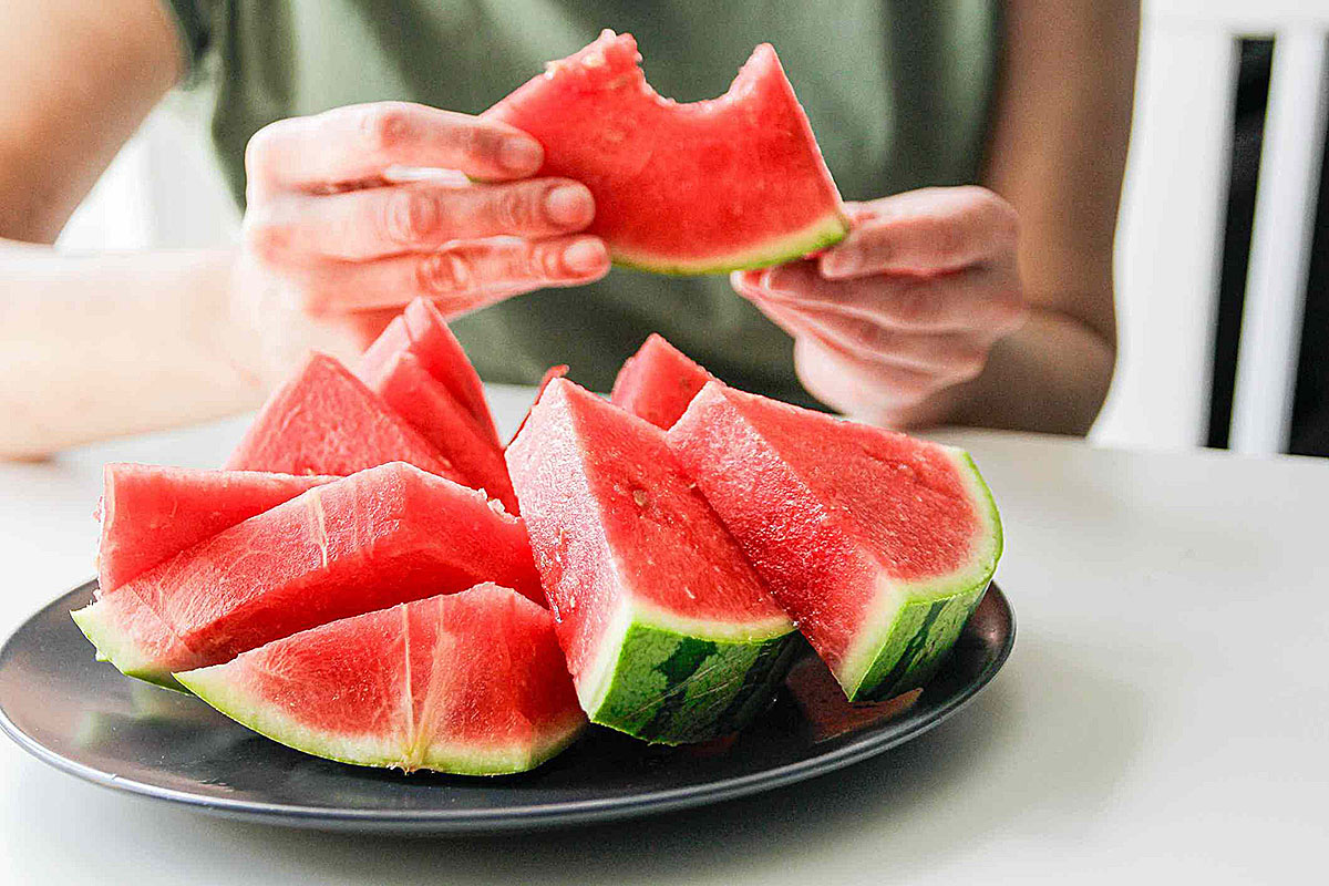 Person eating fresh watermelon slices at dining table healthy summer fruit concept