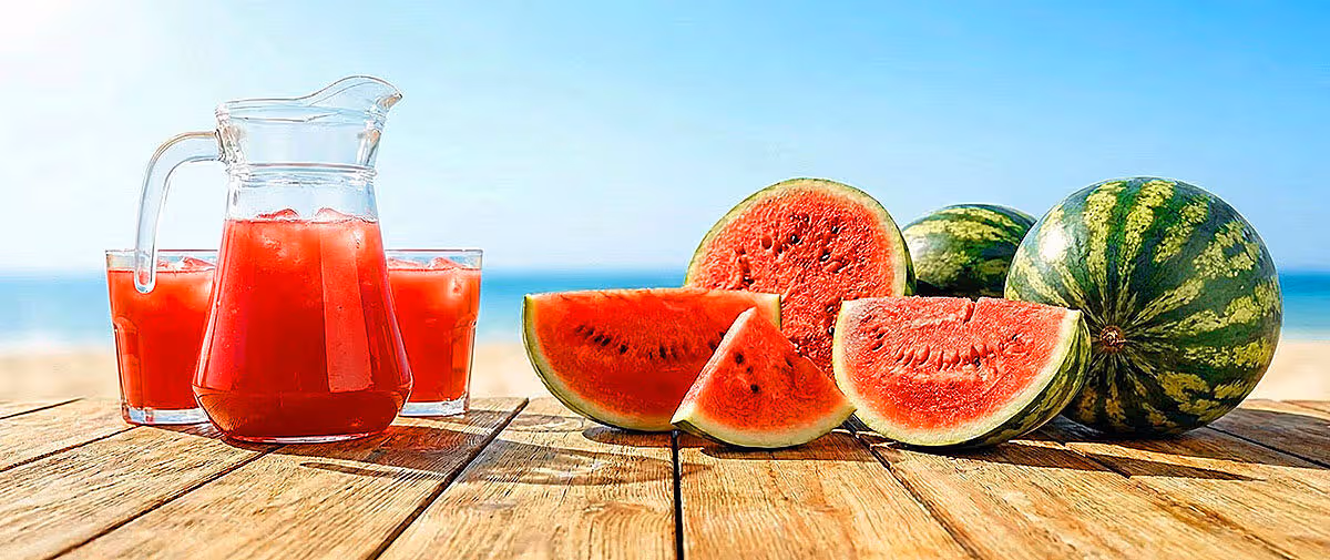 Watermelon juice and sliced fruits on wooden table summer hydration concept