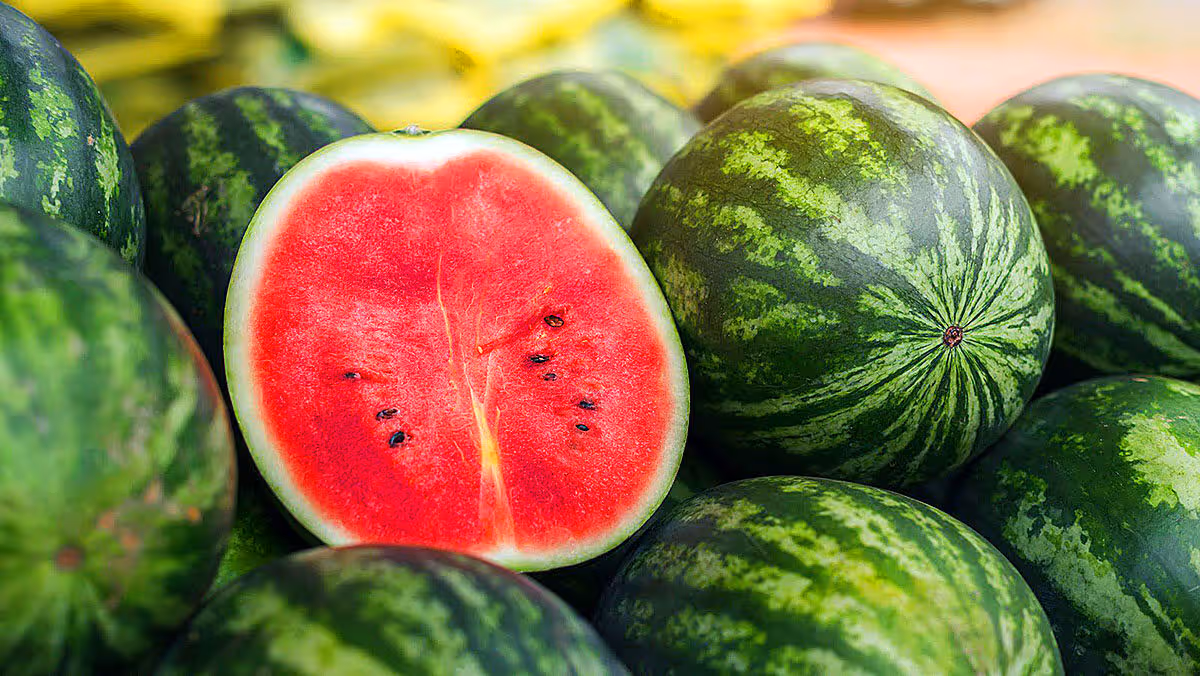 Whole and cut watermelon fruits displayed in market showing fresh red pulp
