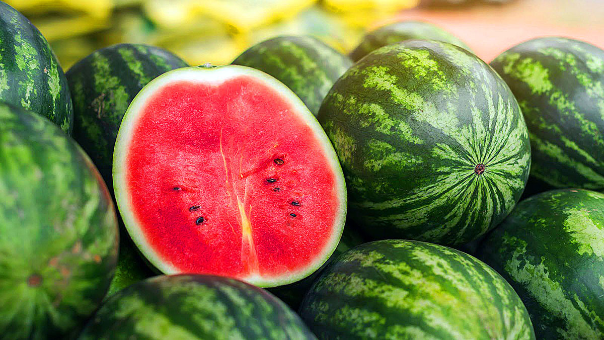 Whole and cut watermelon fruits displayed in market showing fresh red pulp