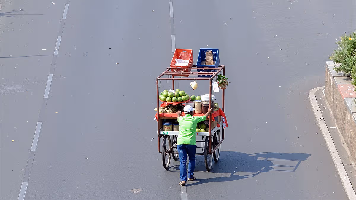 Street vendor pushing cart on empty road during intense summer heat